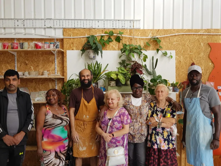 Group of people pose for a photo inside a pottery studio