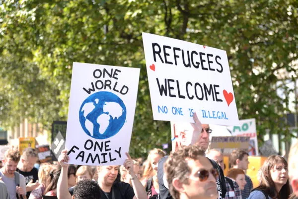 People holding signs, including 'refugees welcome'