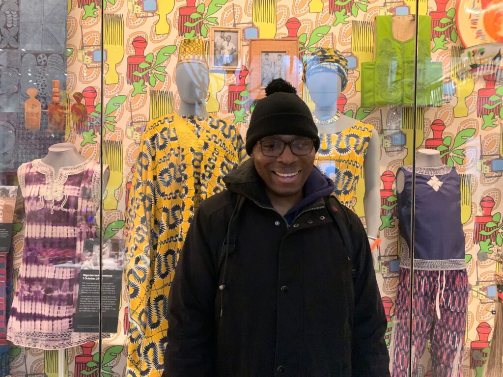 A man smiles for a photo in front a showcase at the Horniman Museum