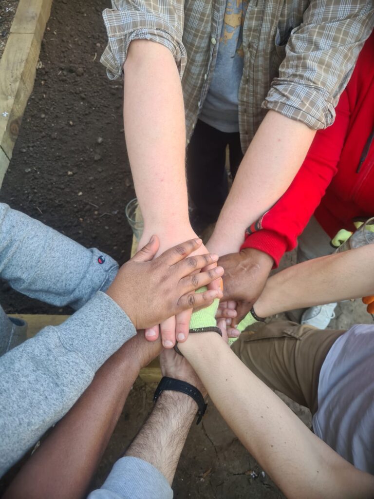A group of people stretch their hands into the middle