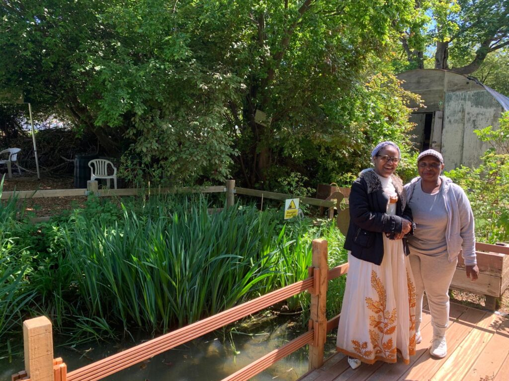 Two women pose by a pond in Brockwell Park