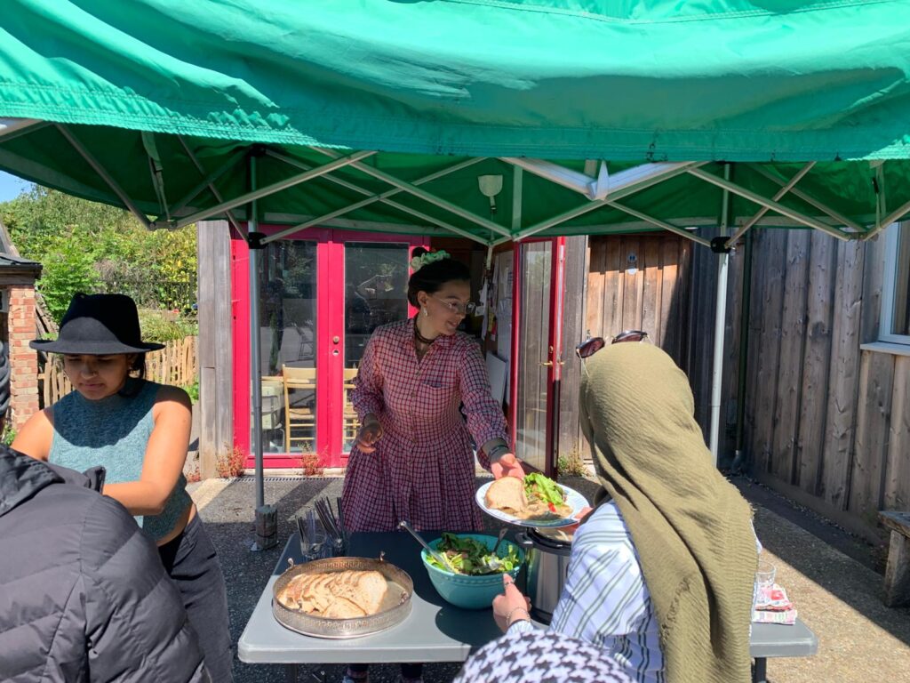 People serve food under a marquee in Brockwell Park