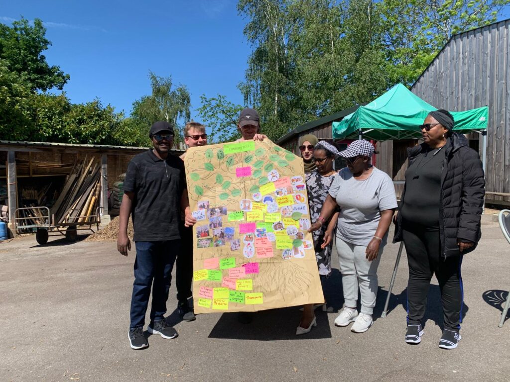 A group of people pose with a large sheet of paper design to look like a tree
