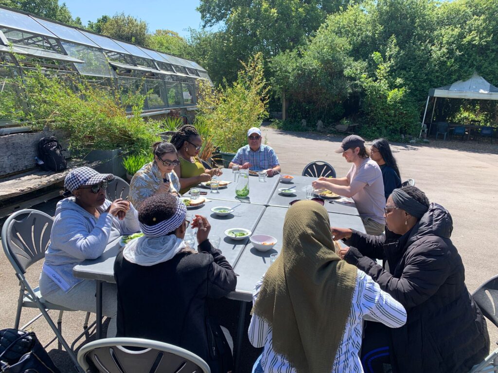 A group of people eat lunch together at Brockwell park