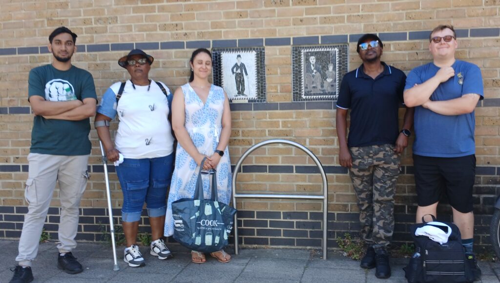 A group of people pose for a photograph in front of Charlie Chaplin mosaic