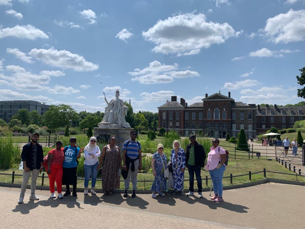 A large group of people pose in front of Kensington Palace in London
