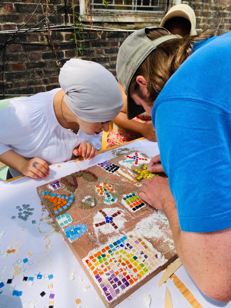 Two people work on a mosaic together