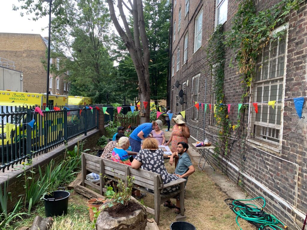 People mill around a table in a garden, London